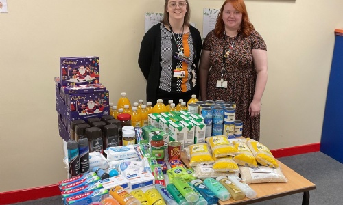 Photo of 2 staff members with a table of food donations.